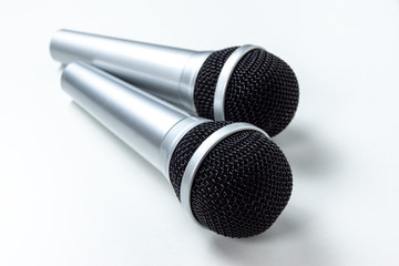 two black microphones without cords on a white table