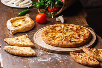 Caucasian Georgian kitchen. Bakery products. Pie with cheese. Set from khachapuri, Imeretian, Megrelian and Adjarian. On the wooden table.