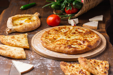 Caucasian Georgian kitchen. Bakery products. Pie with cheese. Set from khachapuri, Imeretian, Megrelian and Adjarian. On the wooden table.