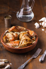 Roasted chicken with creamy garlic sauce in cast frying pan on wooden background