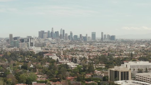 AERIAL: View over Los Angeles, California with Downtown in Background and Beautiful Rich Green Trees and Residential Houses on Overcast Day 