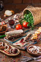 a lot of different dishes on the holiday table. Georgian Cuisine, roasted meet, greens, vegatables, barbeque, red sauce.