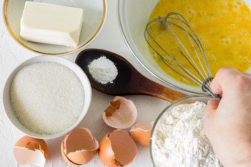 hand with a whisk over the ingredients for making short pastry for a pie