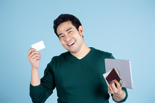 Happy Asian Tourist Showing Credit Card And Tablet, Map, Passport With Blue Background.