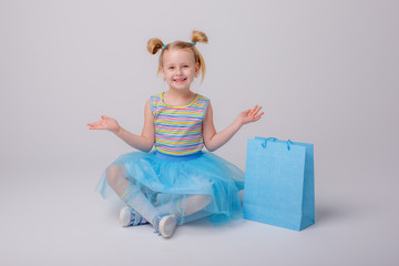 a little girl with a shopping bag sits on a skate Board on a white background