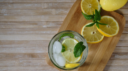 Lemonade with lemon, mint and ice on wooden table. View from above with copy space. 