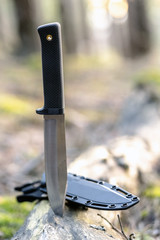 tactical knife in forest. With blurred background. Survival tools. Toy for man