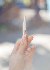 A man holding up a new smoking device with a cigarette inside, on a sunny day with bokeh in the...