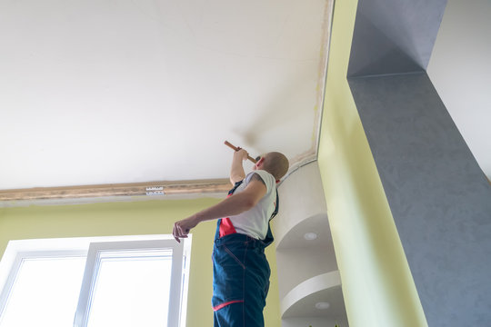 Worker Knocks On The Ceiling With A Hammer, Wiring Installation