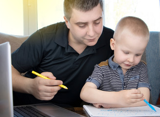Dad and son do their homework, study online on the Internet. The concept of preschool education, home schooling of quarantined children during the coronavirus pandemic, covid-19