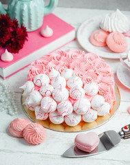 cake greased with pink cream and decorated with meringues