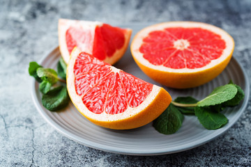 Red grapefruit with slaces and mint leaves on a light background