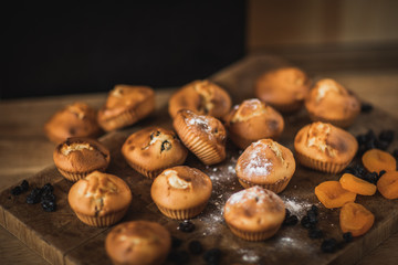 Freshly baked muffins with raisins and dried apricots, shot on a dark background. Background for baking and cooking.