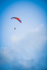 Skydiver flies on a red parachute in the blue sky