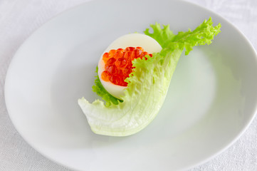 egg half with red caviar in iceberg lettuce leaf