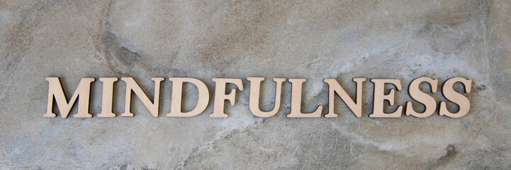 mindfulness , writen wooden letters on stone background
