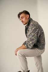 Hombre en chaqueta militar sentado en estudio