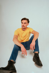 Model poses in blank studio in jeans and yellow t-shirt