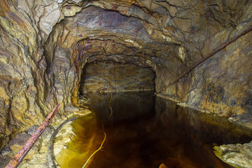 Abandoned copper ore mine underground tunnel with yellow water
