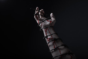 Concept photo of a hand and arm tied with barbed wire artistic conversion