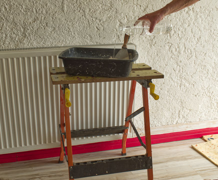 D&eacute;pose d'enduit, de pl&acirc;tre sur un mur par un pl&acirc;trier et pr&eacute;paration du m&eacute;lange dans une auge pour boucher et lisser l'enduit sur la paroi &agrave; l'aide d'un couteau et d'une spatule