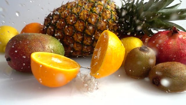 Fall of orange against the background of tropical fruits. Slow motion.