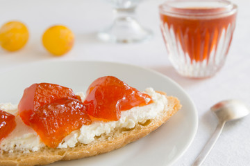 open sandwich with butter and yellow plums jelly, cristal jar, and plums