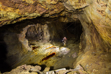 Abandoned copper ore mine underground tunnel with miner explorer