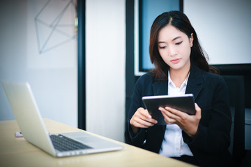 Asian business women using tablet  for working at office relax time and smiling