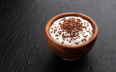 Fresh yogurt with flax seeds on black background