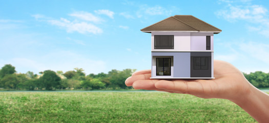 Mortgage concept by money house. holding  house model in hand