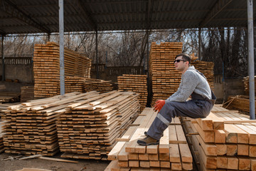 Fototapeta premium Portrait of young man carpenter at the wooden warehouse is resting