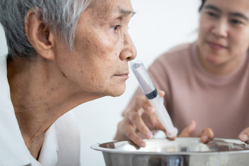 Nasal irrigation,asian caregiver is helping senior woman wash away dirt her nasal,nose cleaning,elderly people having allergic to weather,irrigation prevent allergies,air pollution,smog,dust of PM2.5