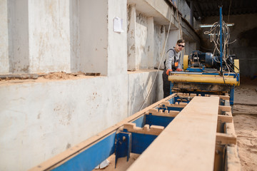 Young man carpenter at the wooden sawmill