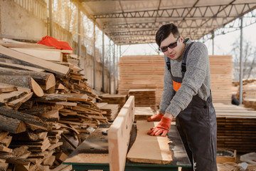 Young man carpenter at the wooden workshop