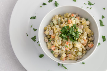 bowl of russian salad dressed with mayonnaise and decorated with  parsley