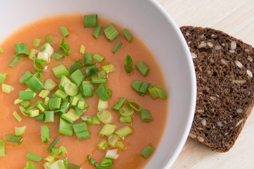pumpkin soup puree decorated with green onion and served with grain bread