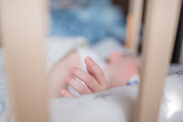 Sleeping baby, hand in crib