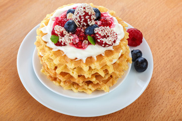 Fresh blueberries, raspberries, waffle cookies on a wooden background