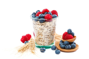 Fresh blueberries and raspberries, oatmeal in a bowl with a wooden spoon