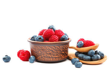 Fresh blueberries and raspberries in a bowl with a wooden spoon