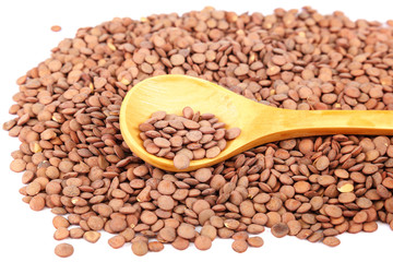 Grains of lentils with a wooden spoon as a background