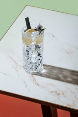 Gin tonic cocktail, with lemon and blooming rosemary, on a small table. Vintage aesthetic
