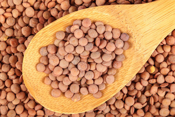 Grains of lentils with a wooden spoon as a background