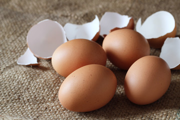 Fresh chicken eggs and cracked egg shell on burlap sack, concept for homemade organic food