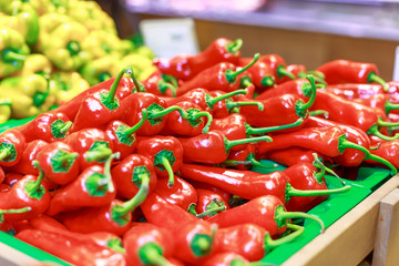 red pepper, behind it yellow pepper on the counter in the store
