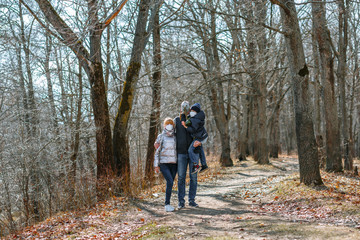 Fototapeta premium A small family in sanitary masks on a walk in the Park. People walk in the conditions of the quarantine