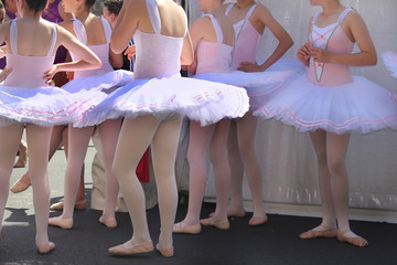 Local suburban street fair. A troop teenage ballerinas is preparing entertain the the crowd at a street fair.  The young teenage girls are backstage.