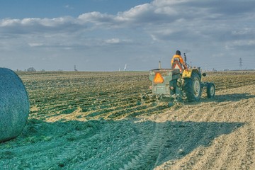 traktor sadzący ziemniaki, wiosna na polach, prace polowe wiosną, rządki posadzonych ziemniaków, słoneczna wiosenna pogoda