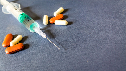 Fototapeta na wymiar Capsules and syringe on dark background. medical capsules with syringe isolated. selective focus. Copy space.